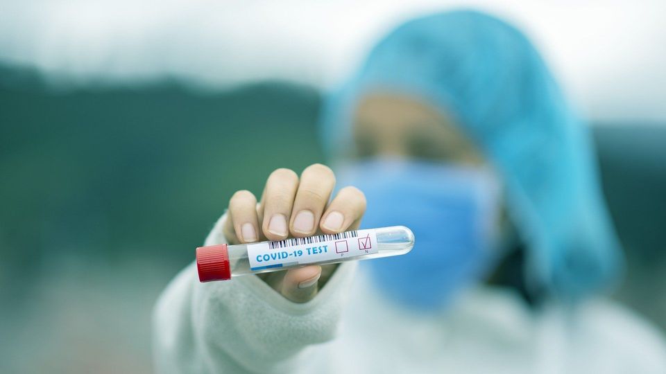 Healthcareworker holding a test tube with the words Covid-19 test on