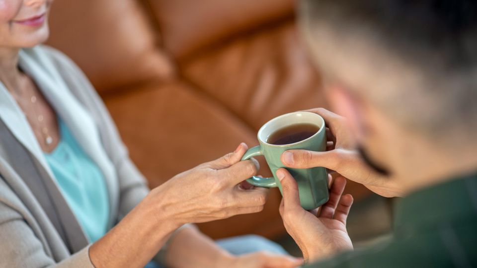 Person passing another a cup of tea