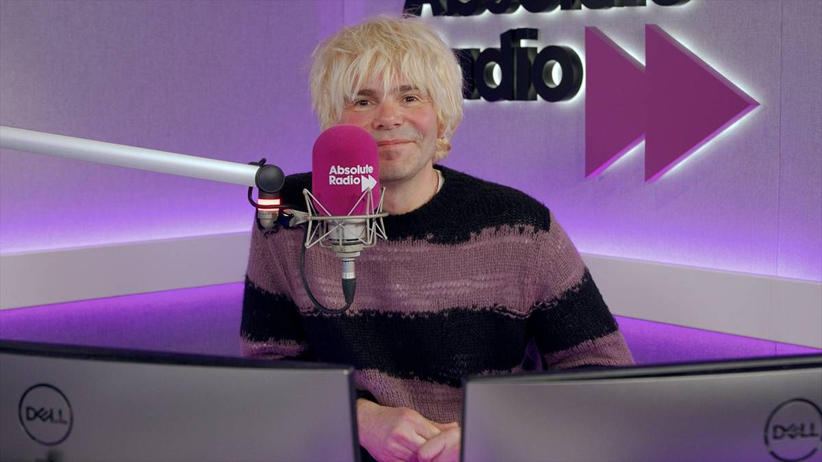 Tim Burgess sitting in front of a microphone with a purple Absolute Radio background
