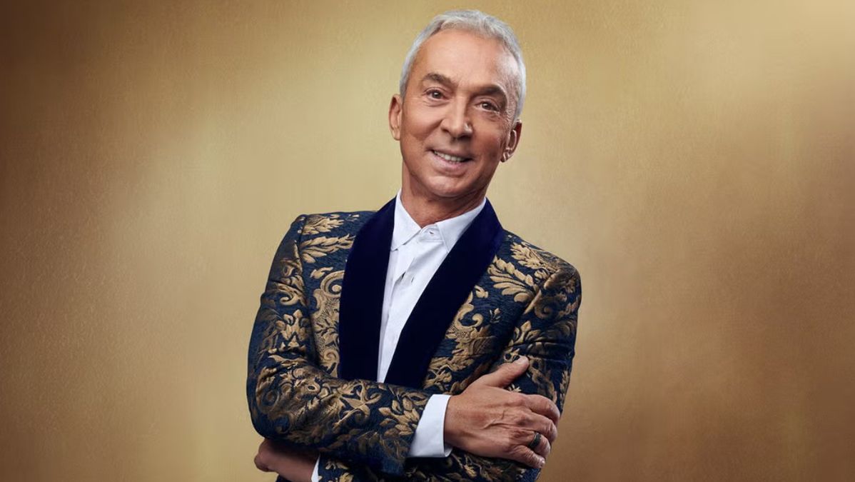 Bruno Tonioli posing for a photo with his arms folded whilst wearing a black and gold suit